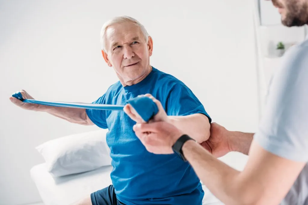 Patient âgé en séance de physiothérapie à domicile avec Qlick&Care